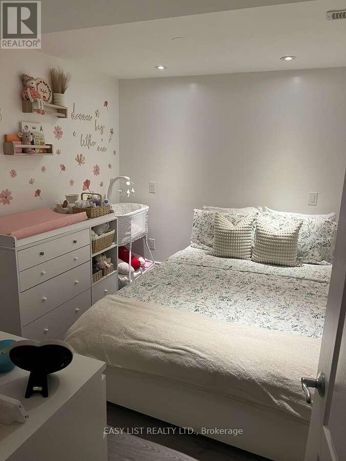A bedroom with a white bed, a pink changing table, and a white dresser.