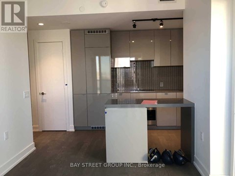 A kitchen area with a white door and a counter with a few bags on the floor.