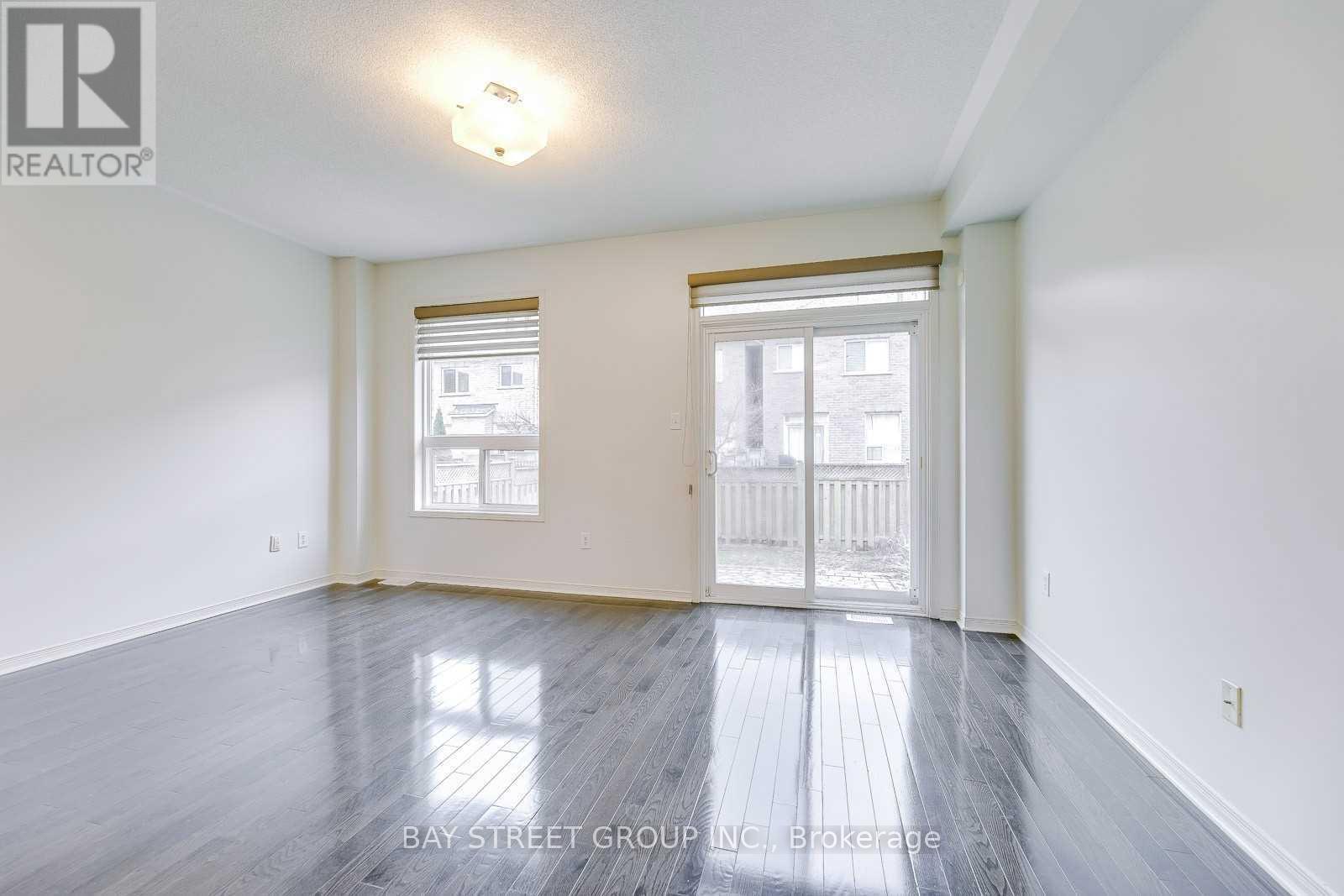 A spacious room with wooden floors and a large window.