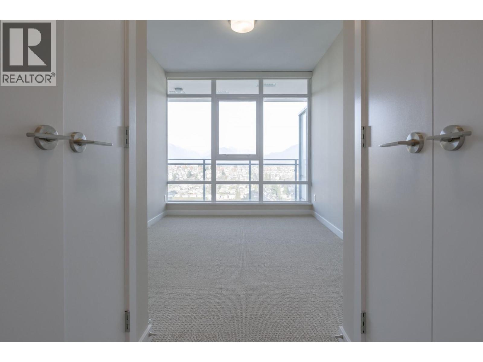 A hallway with a carpeted floor and white walls leading to a door with a window.