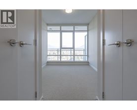 A hallway with a carpeted floor and white walls leading to a door with a window.