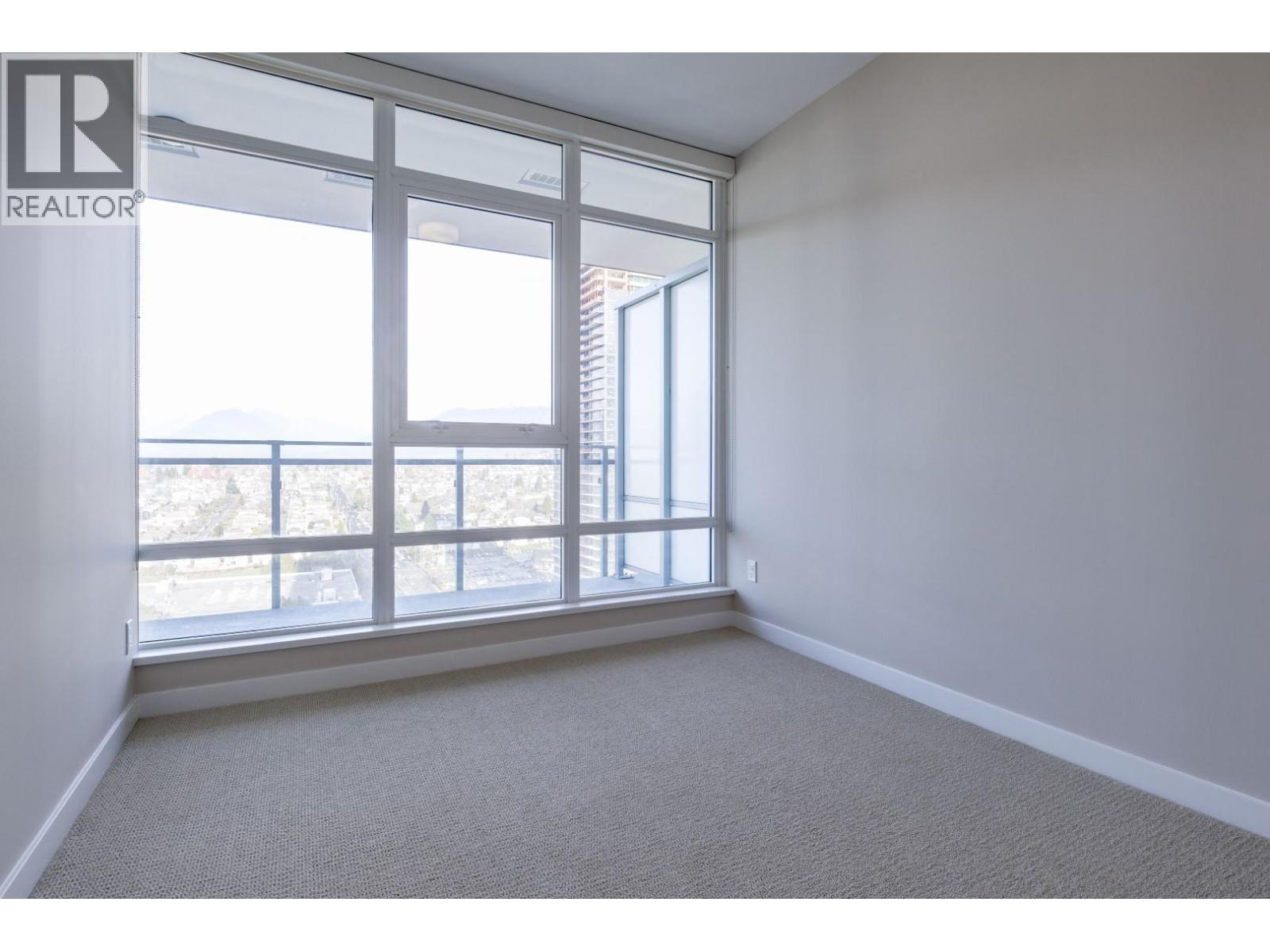 A room with a large window and a carpeted floor.