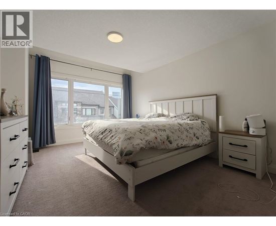 A bedroom with a bed, nightstand, and window.