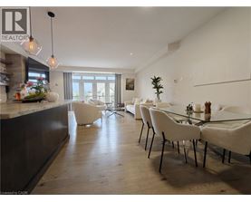 A modern dining room with a glass table and white chairs.