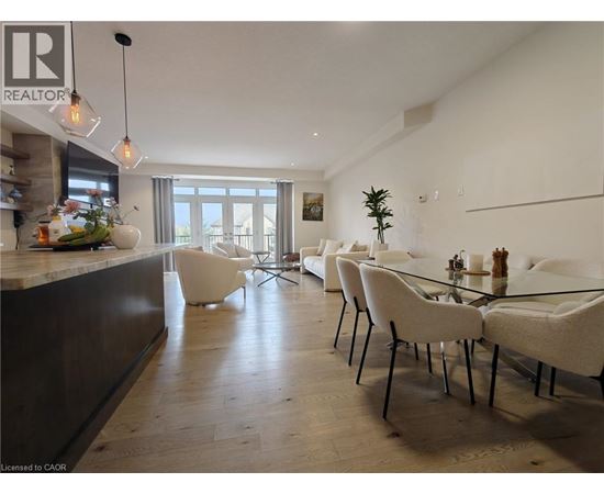 A modern dining room with a glass table and white chairs.