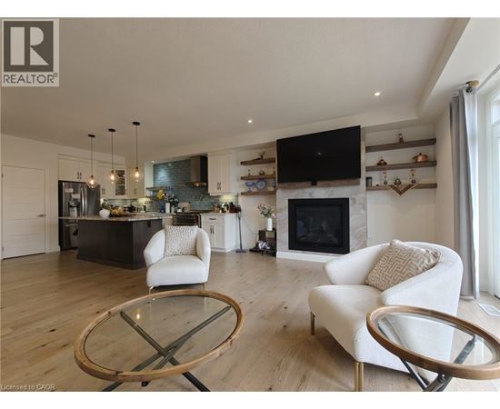 A modern living room with a glass table and white chairs.
