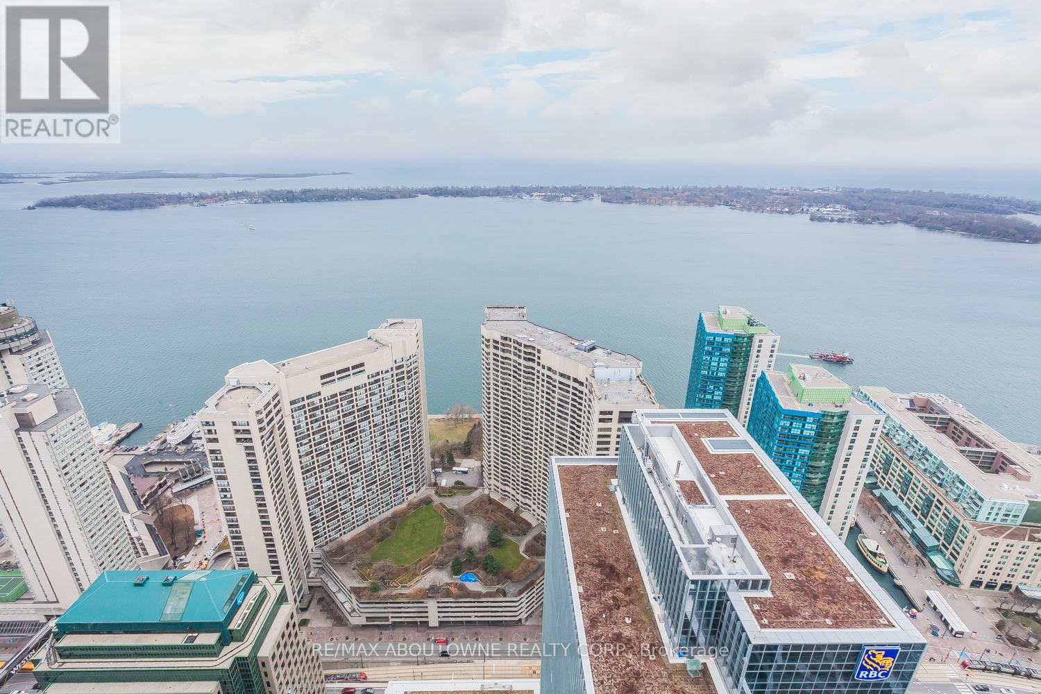 A cityscape with a body of water in the background and a building with a green roof in the foreground.