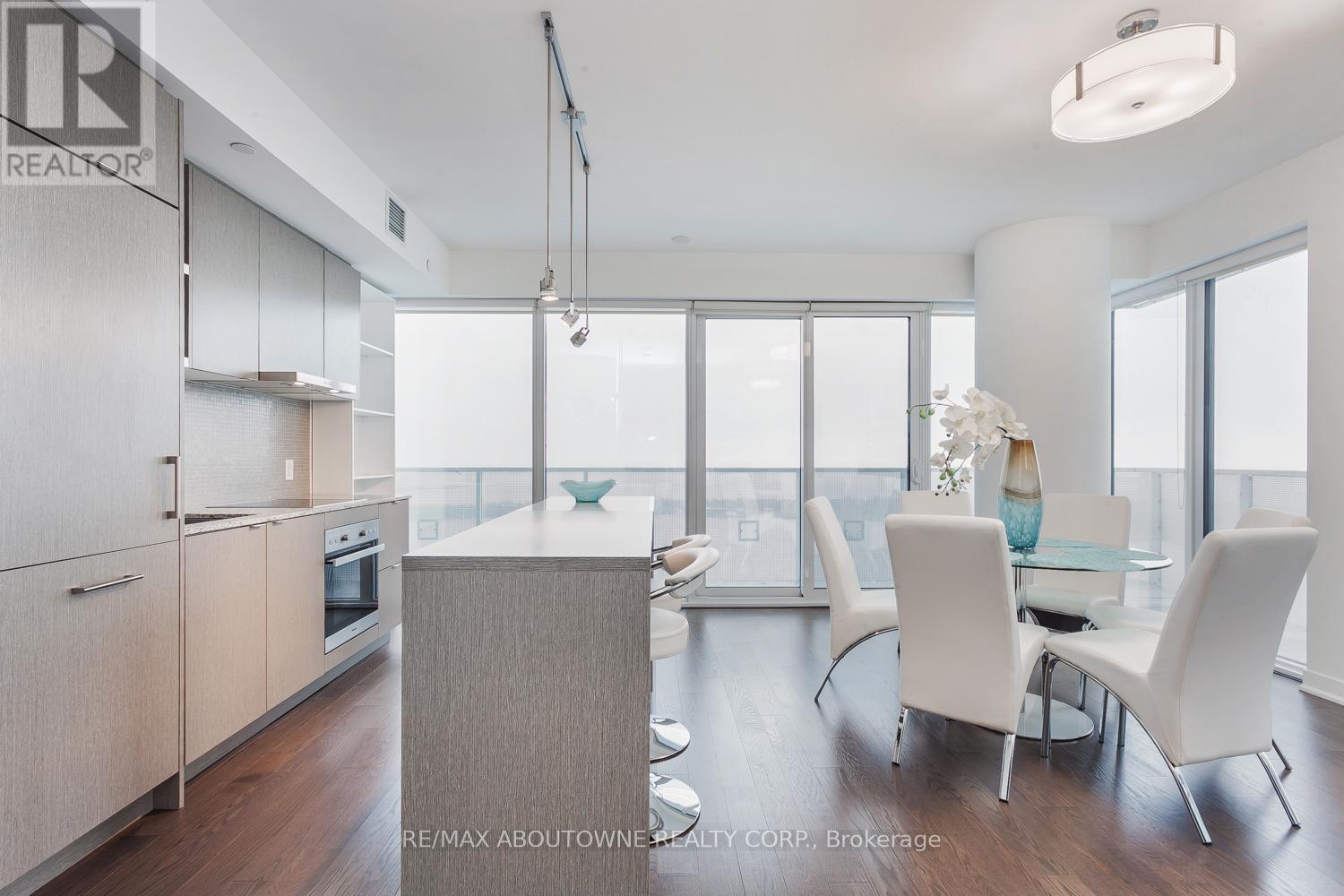 A modern kitchen with white chairs and a glass table.