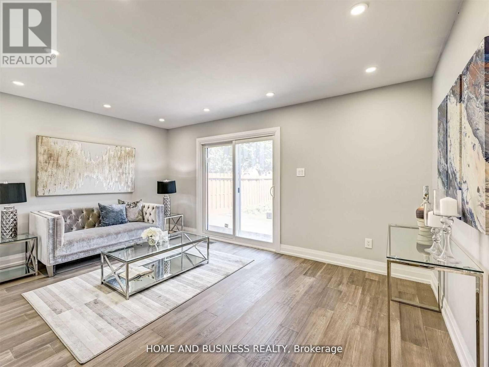 A spacious living room with a glass coffee table and a large painting on the wall.