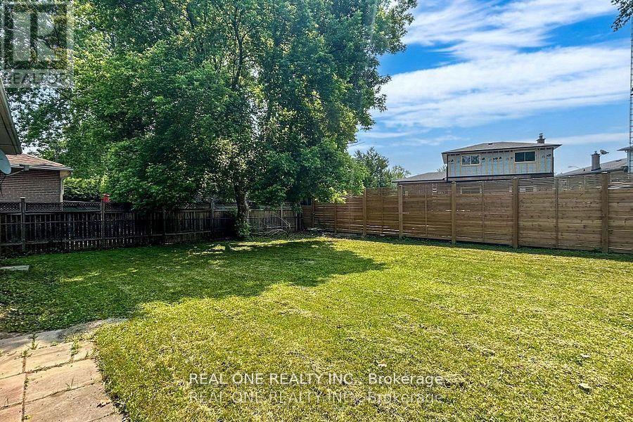 A backyard with a wooden fence and a small building in the background.
