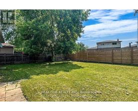 A backyard with a wooden fence and a small building in the background.