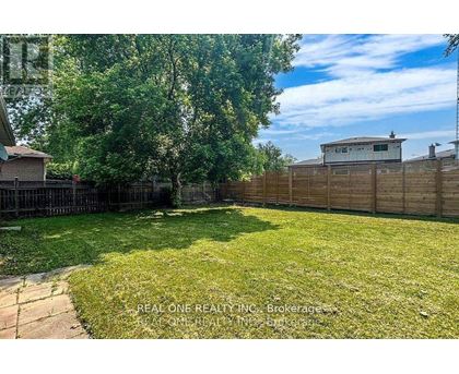 A backyard with a wooden fence and a small building in the background.
