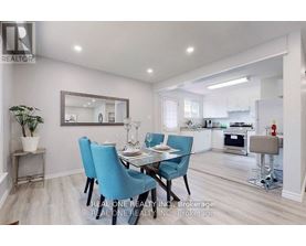 A dining room with a table set for two and a kitchen in the background.