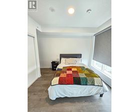 A bedroom with a bed, nightstand, and window.