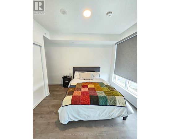 A bedroom with a bed, nightstand, and window.