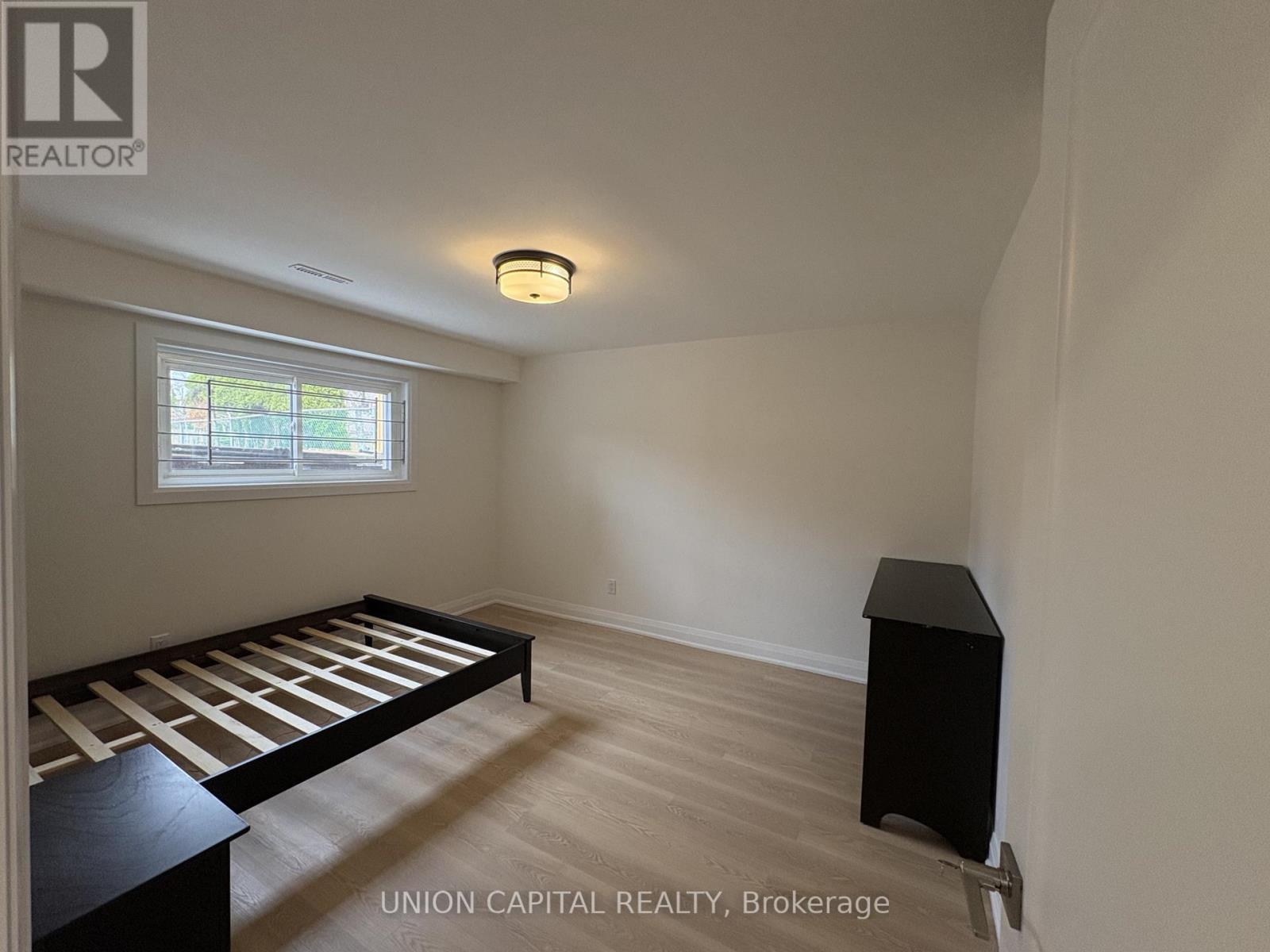 A bedroom with a bed, dresser, and window.