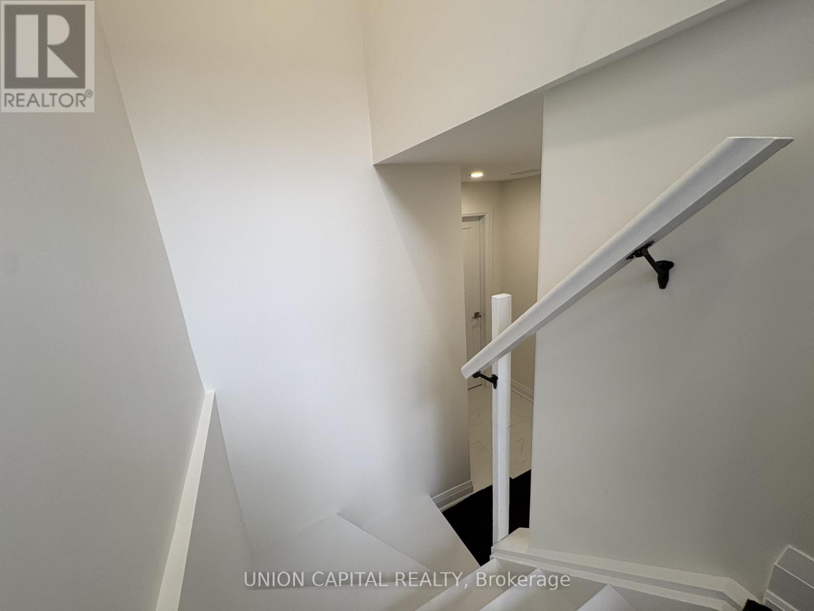 A staircase with a white railing and a black handrail.