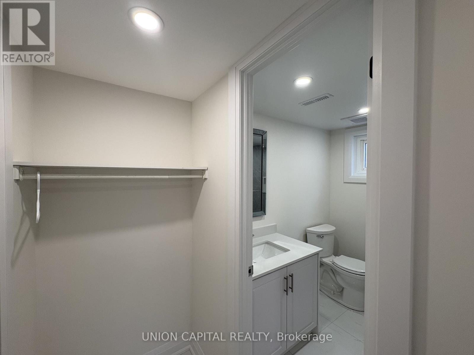 A bathroom with a toilet, sink, and mirror.