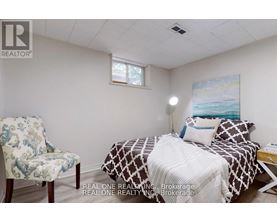 A bedroom with a bed, chair, and painting on the wall.