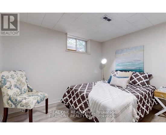 A bedroom with a bed, chair, and painting on the wall.