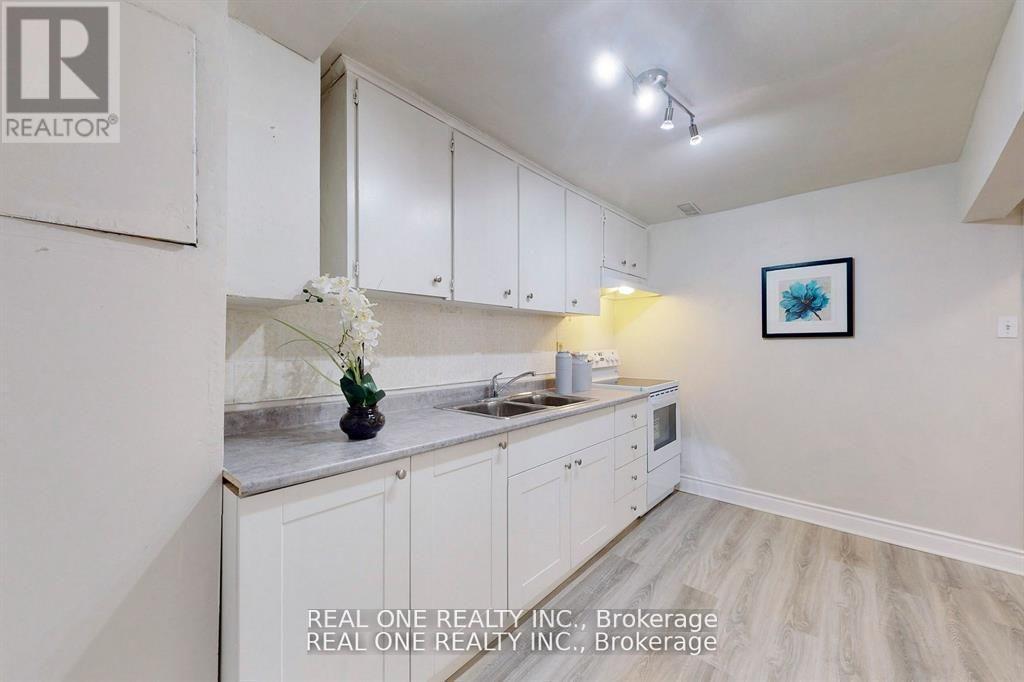 A kitchen with white cabinets and a vase of white flowers on the counter.