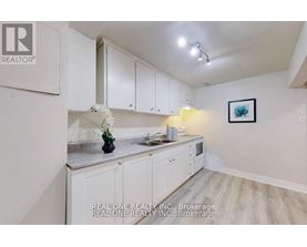 A kitchen with white cabinets and a vase of white flowers on the counter.
