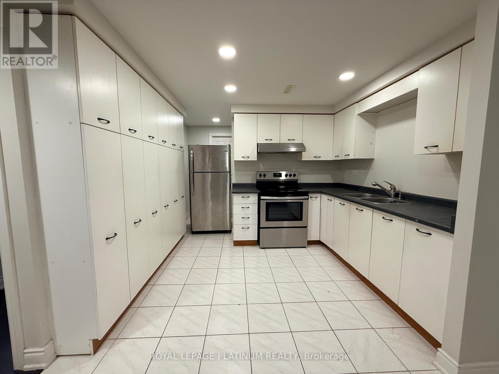 A white kitchen with a refrigerator, oven, and sink.