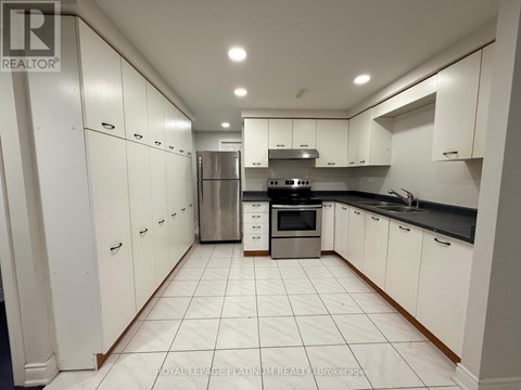 A white kitchen with a refrigerator, oven, and sink.