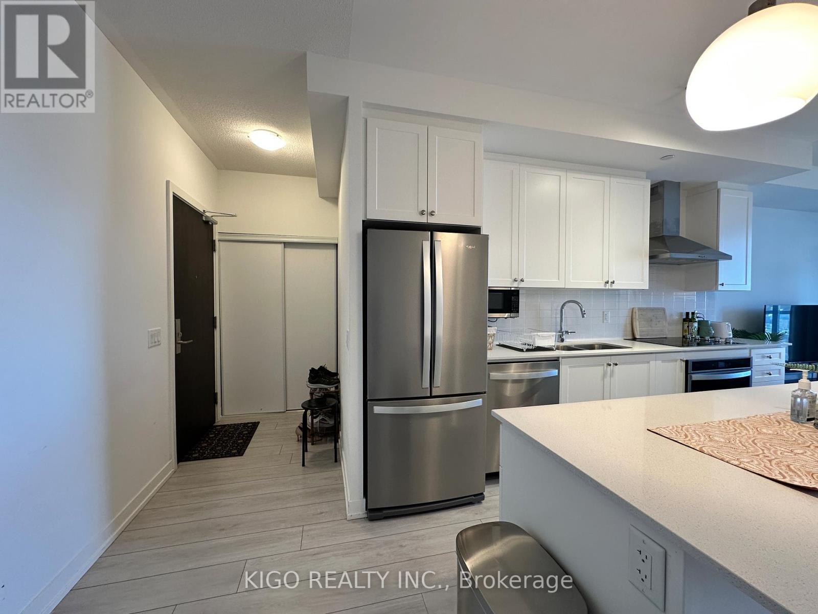 A modern kitchen with white cabinets and a stainless steel refrigerator.