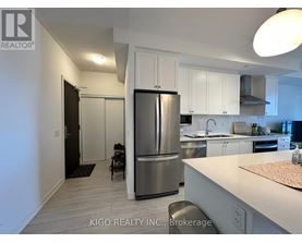 A modern kitchen with white cabinets and a stainless steel refrigerator.