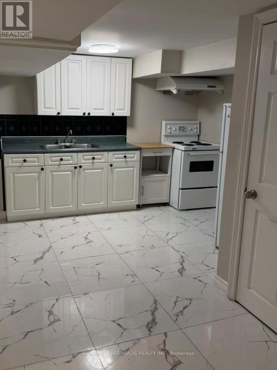 A kitchen with white cabinets and marble flooring.