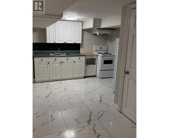 A kitchen with white cabinets and marble flooring.