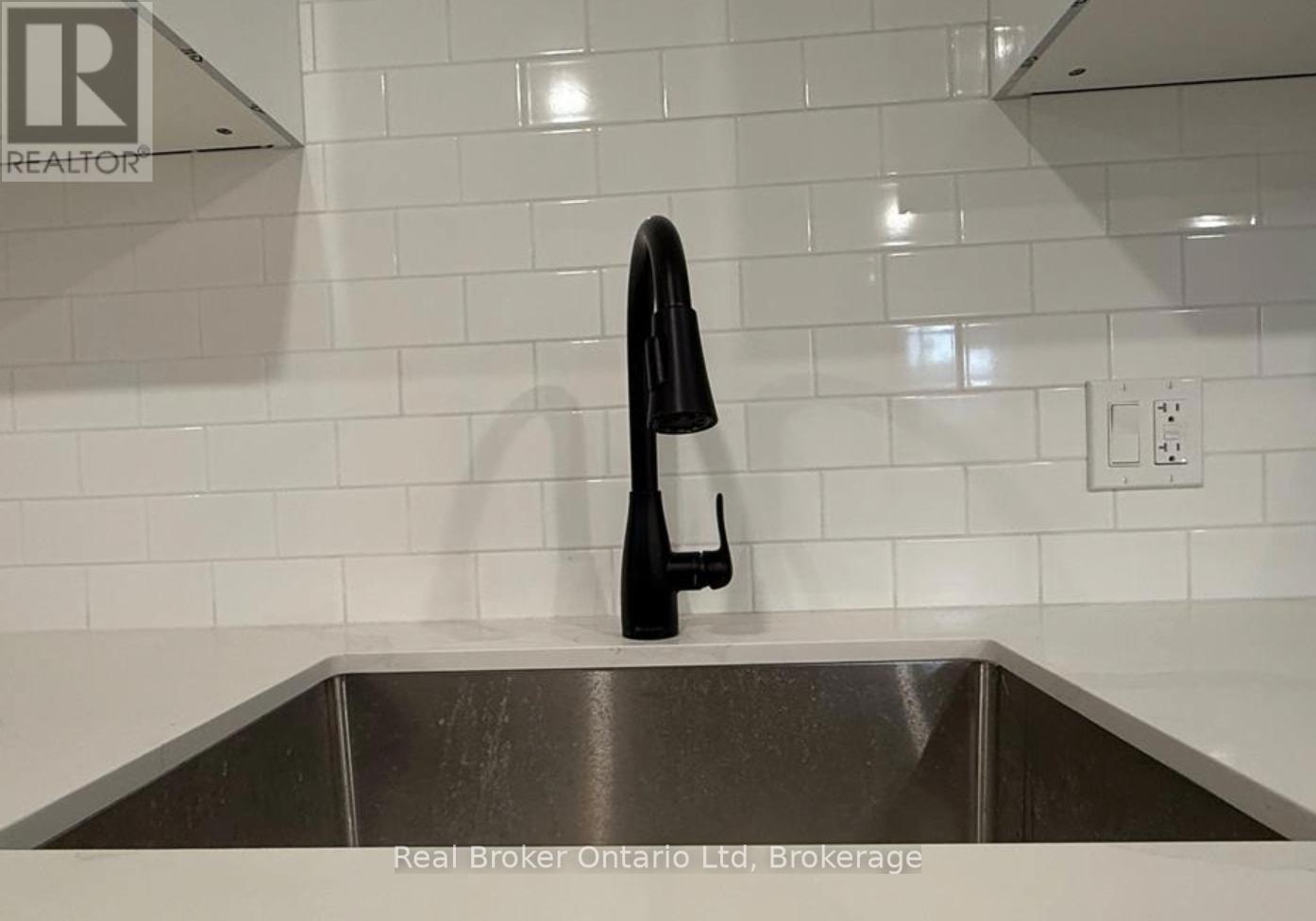 A black bottle is on a stainless steel sink.
