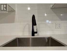 A black bottle is on a stainless steel sink.