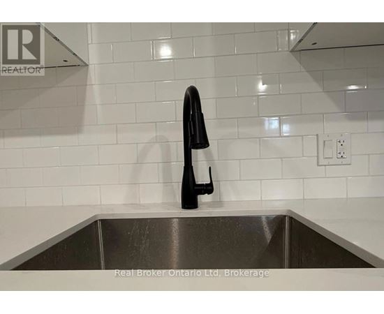 A black bottle is on a stainless steel sink.