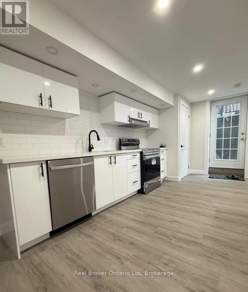 A modern kitchen with white cabinets and a wooden floor.