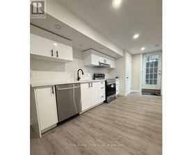 A modern kitchen with white cabinets and a wooden floor.