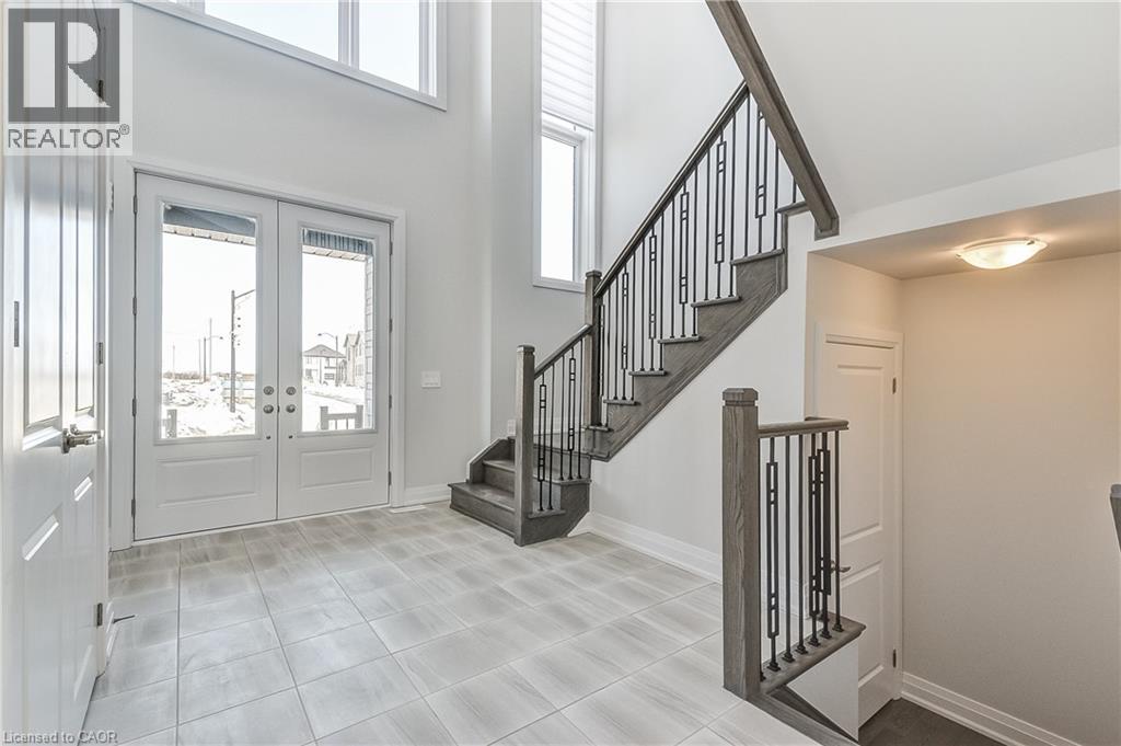 A spacious foyer with a staircase and a glass door leading to the balcony.