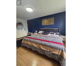 A bedroom with a bed, nightstand, and a wall hanging.