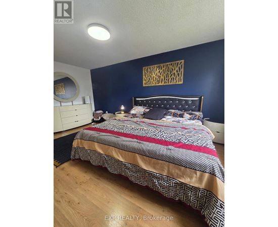 A bedroom with a bed, nightstand, and a wall hanging.