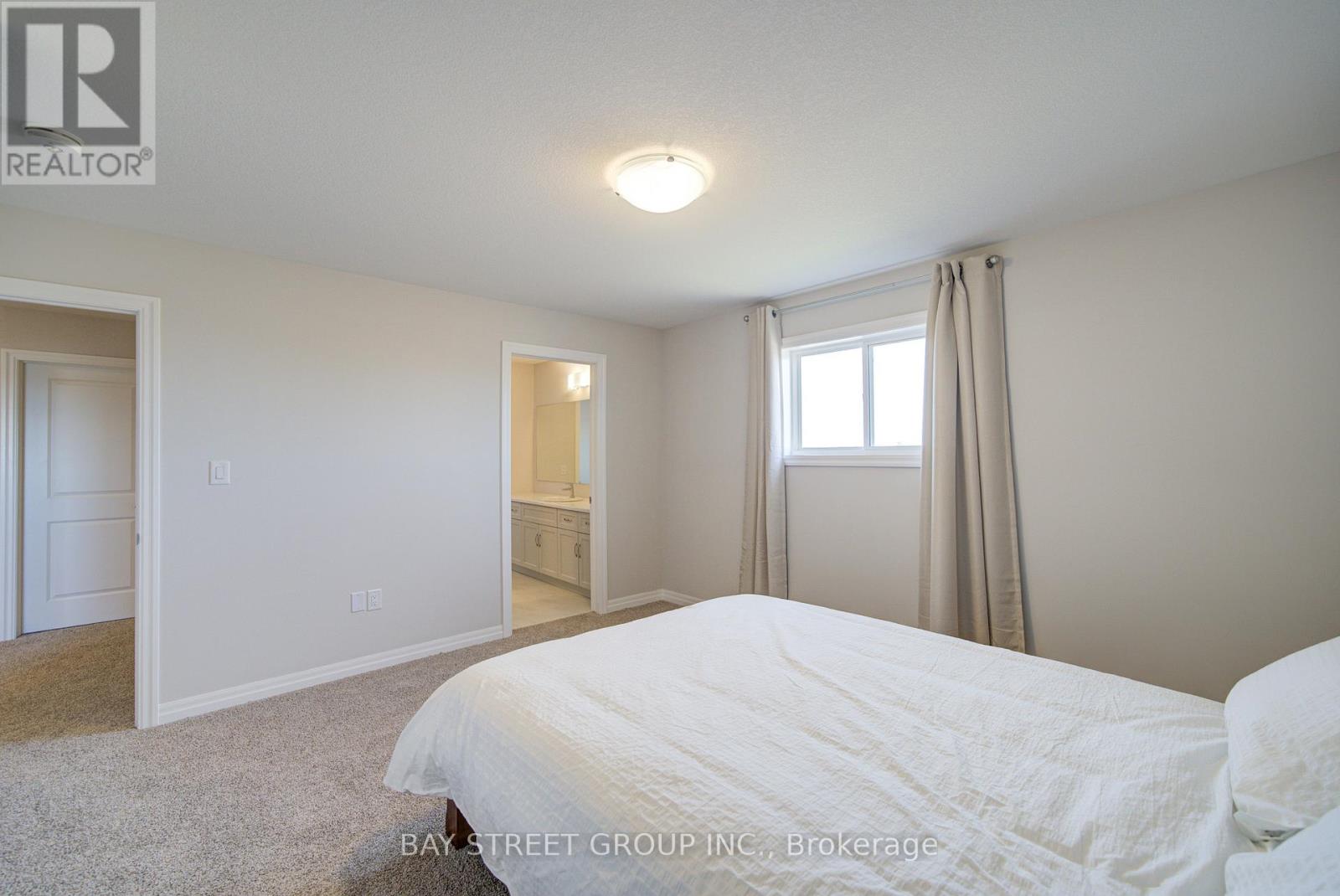 A bedroom with a large bed and a window with curtains.