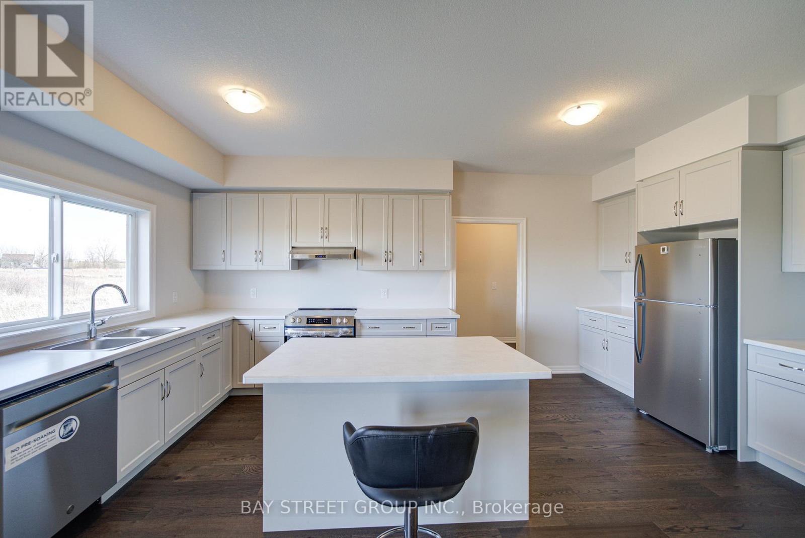 A kitchen with white cabinets and a white island with a black chair.