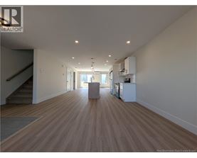 A spacious room with wooden flooring and a staircase on the left side.
