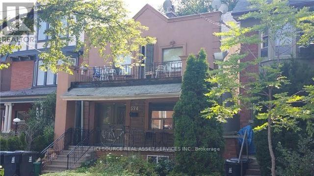 A house with a balcony and a tree in front.