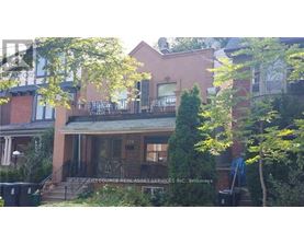 A house with a balcony and a tree in front.