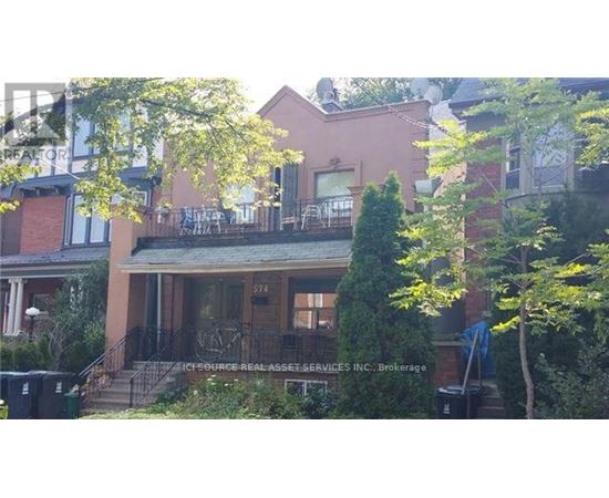 A house with a balcony and a tree in front.