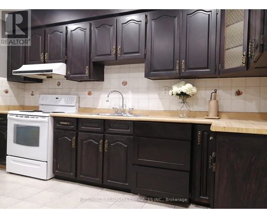 A kitchen with dark brown cabinets and a white oven.