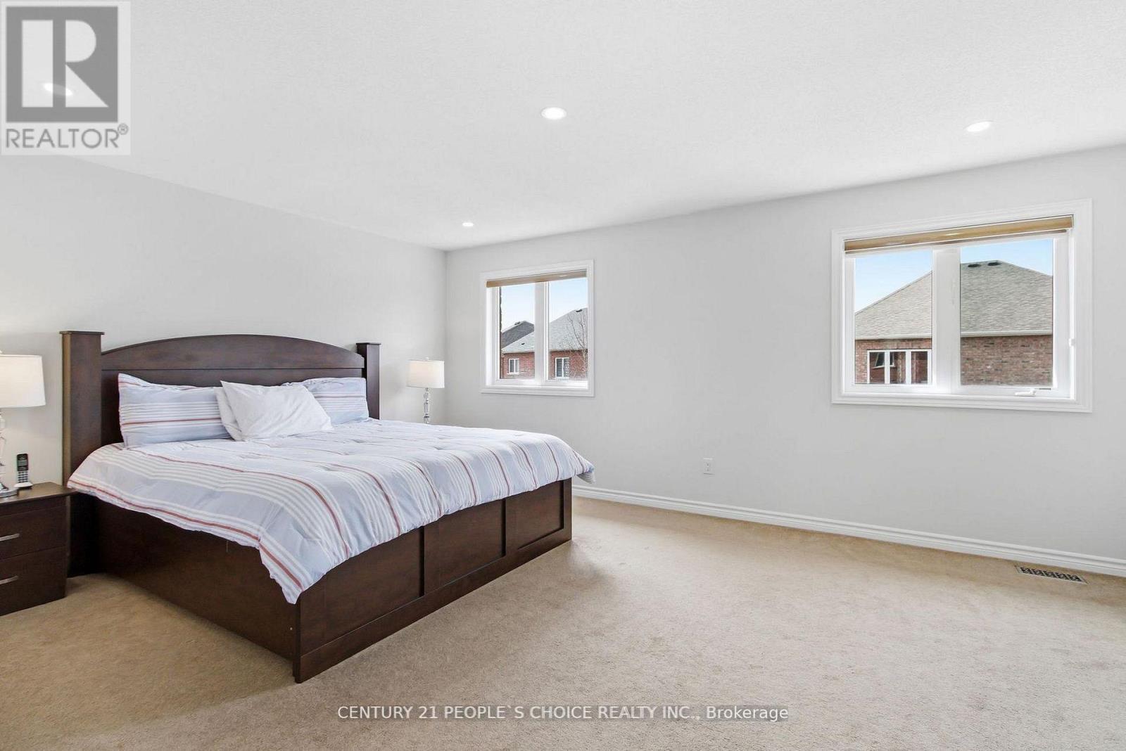 A bedroom with a large bed and a window overlooking a house.