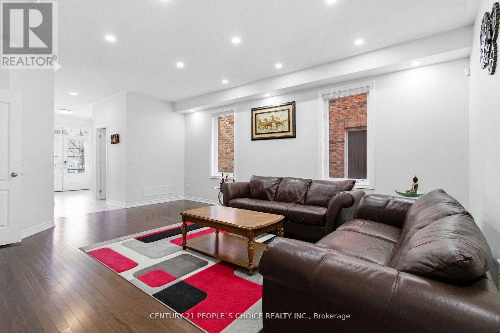 A living room with brown leather couches and a red rug.