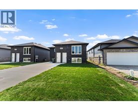 A realtor photo of a house with a well-maintained lawn and a clear sky.